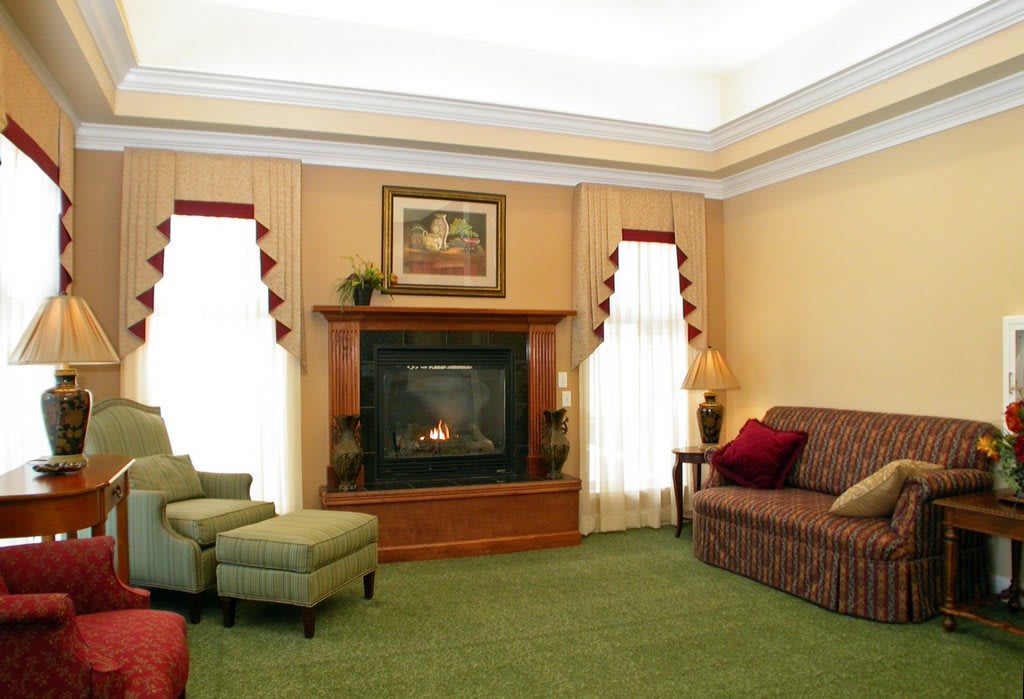 A cozy living room featuring a fireplace, upholstered furniture, and elegant drapes.