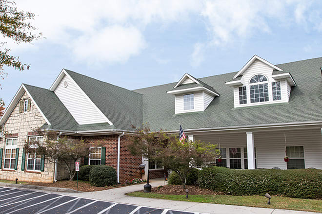 A suburban residential house with a green roof and brick exterior.