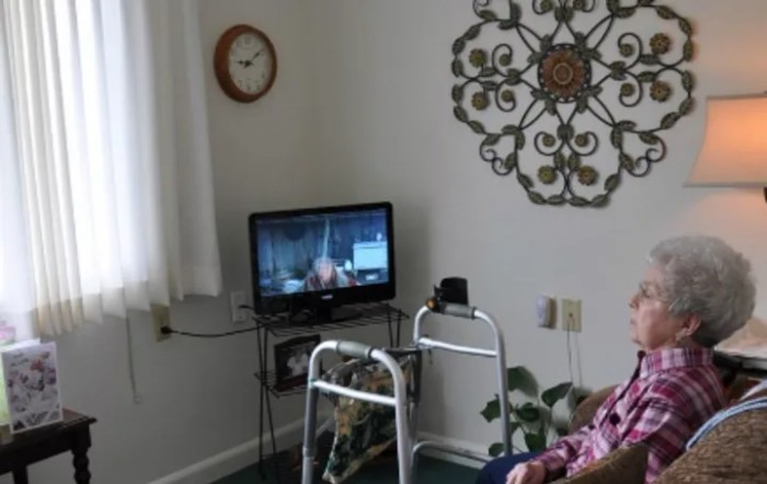 A cozy living room setting with a television, walker, and decorative wall art.