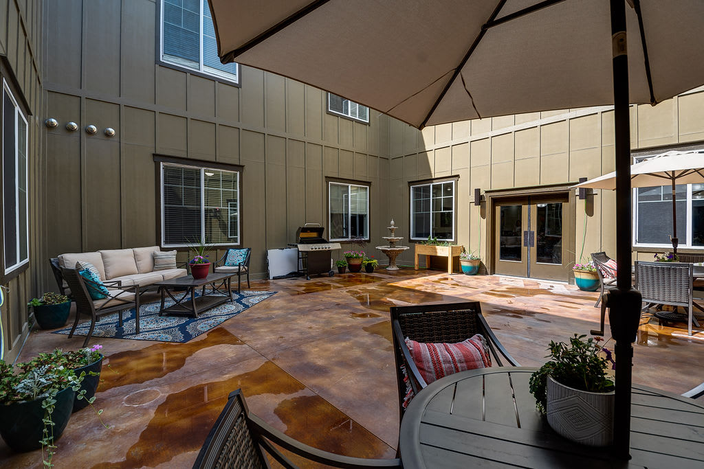 A spacious patio with outdoor seating, a large umbrella, and access to the house through multiple windows and doors.