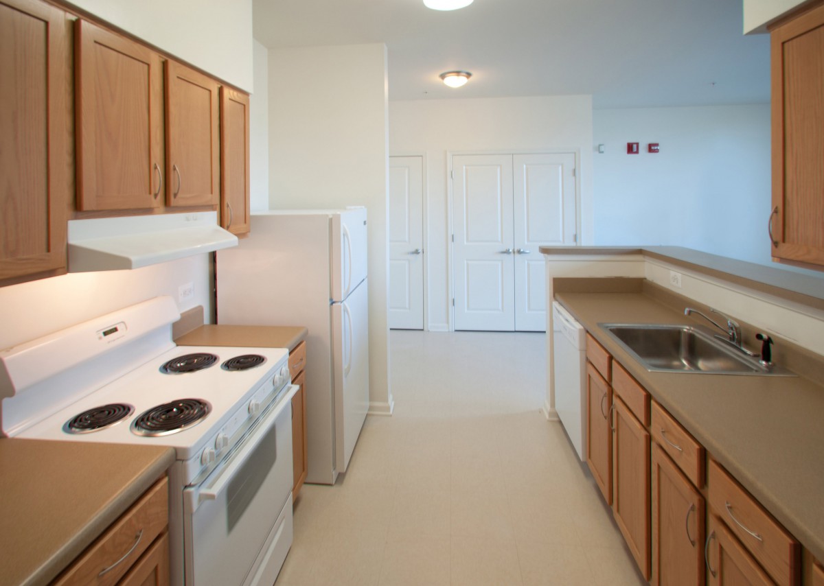 A modern kitchen with wooden cabinets, a stove, and spacious countertops.