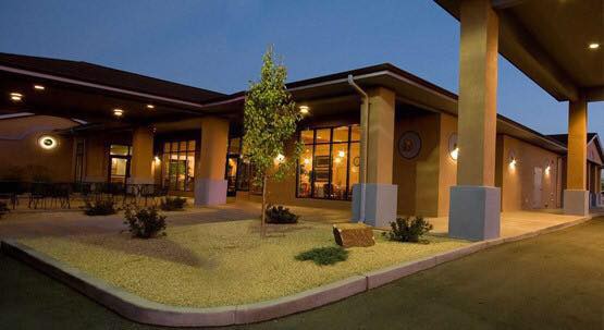 A modern building illuminated at night with landscaped surroundings.