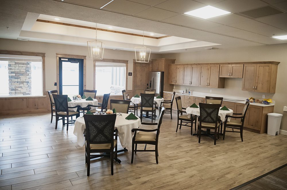 A spacious dining area with several tables and chairs, featuring wooden cabinets and bright lighting.