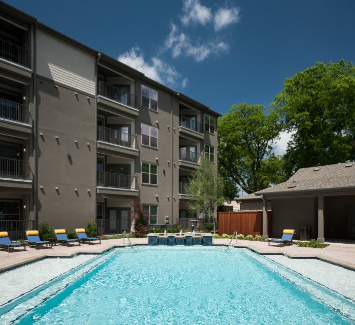 A residential apartment complex with an outdoor swimming pool on a sunny day.