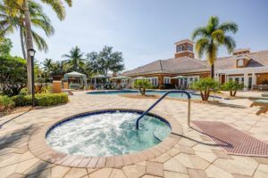 A luxurious resort features a hot tub and pool surrounded by palm trees.