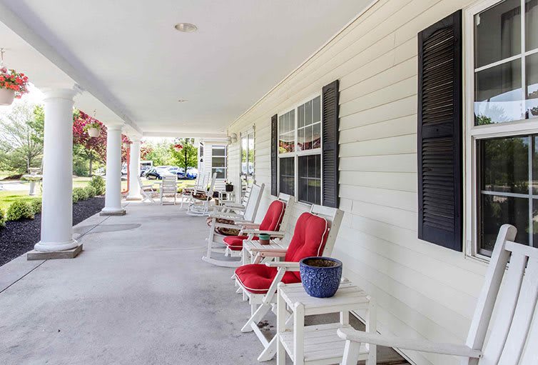 A spacious porch with red-cushioned rocking chairs, perfect for relaxing outdoors.