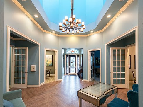 A modern entrance hall with a central chandelier and glass-paneled doors.