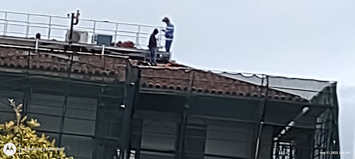Two workers on a roof, engaged in construction activities.