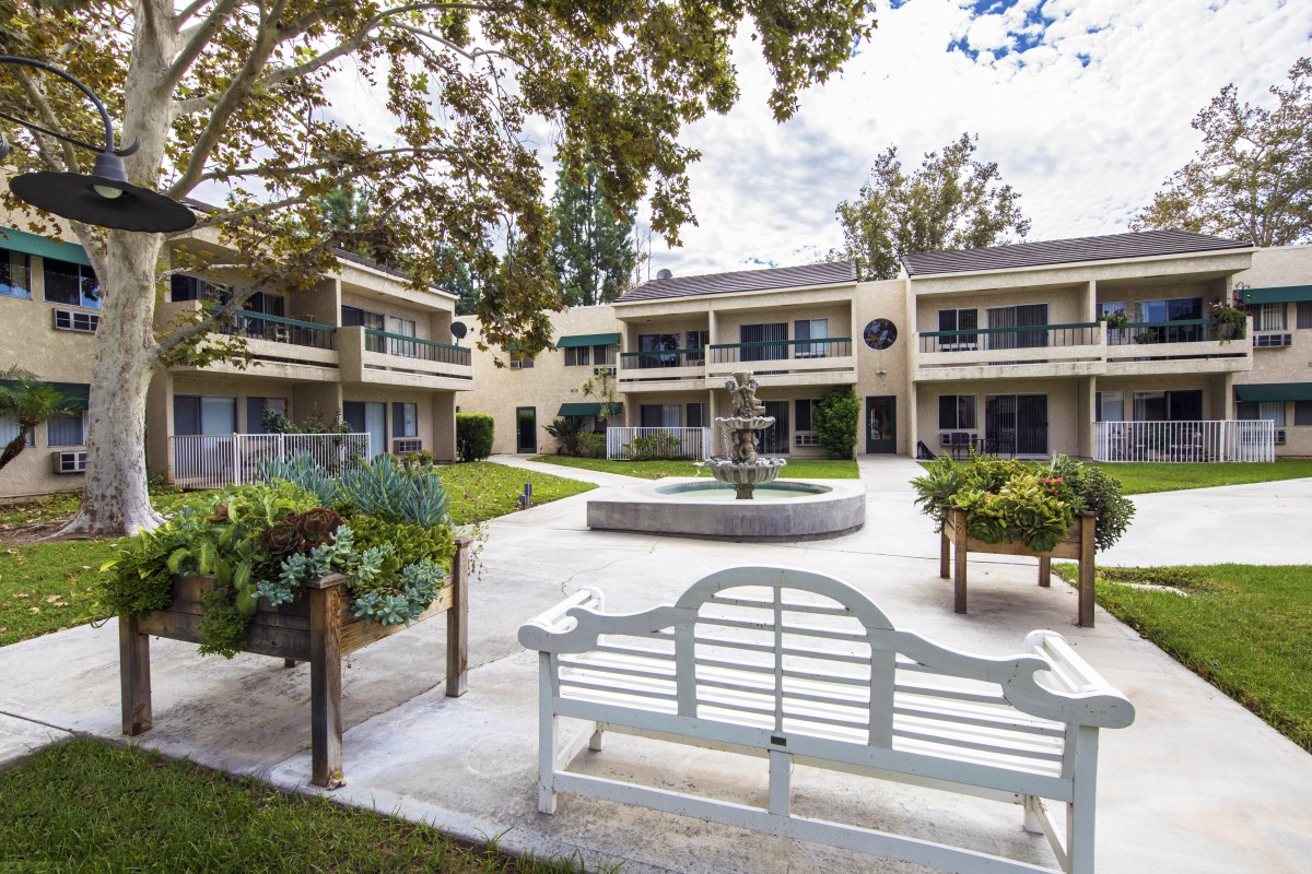 A peaceful courtyard with a central fountain surrounded by a two-story building.