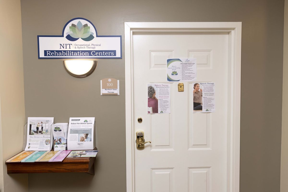 An office door with various flyers and signs displayed, featuring a shelf with informational pamphlets nearby.