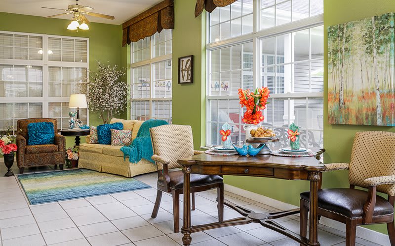 A cozy living and dining area with large windows, adorned with colorful decor and comfortable furniture.