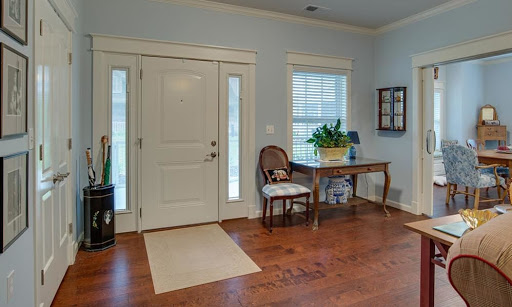 A welcoming entrance with hardwood floors, a small table, and a comfortable chair.