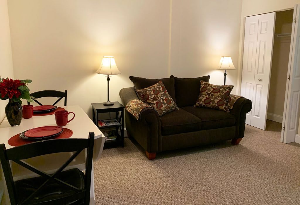 A cozy living room with a sofa, cushions, and warm lighting.