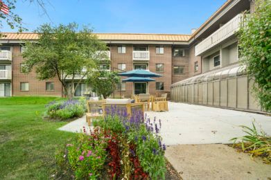 A courtyard with a garden area and seating in front of a multi-story building.