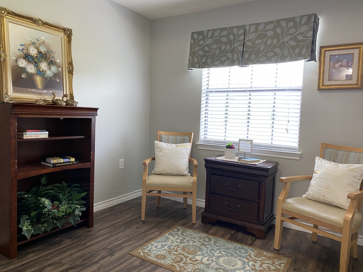 A cozy living room with elegant chairs, a window, and a bookshelf.