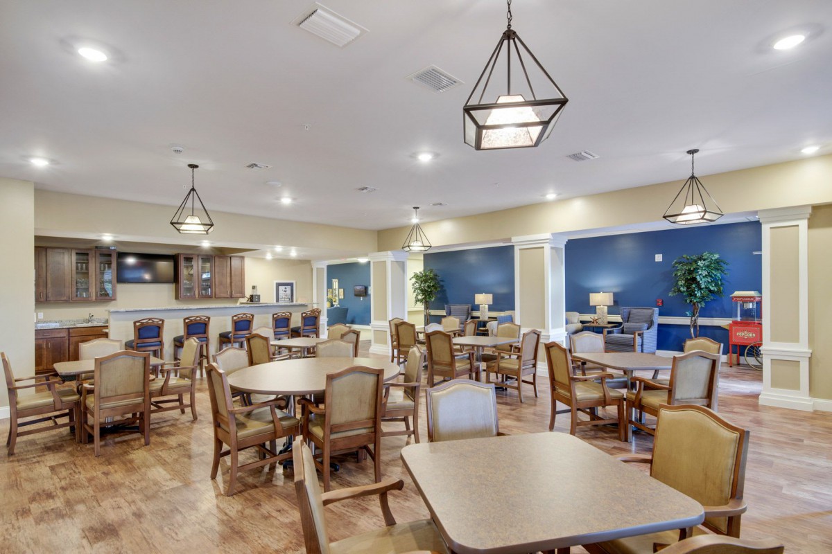 A spacious dining area with tables and chairs arranged neatly, featuring modern lighting and decor.