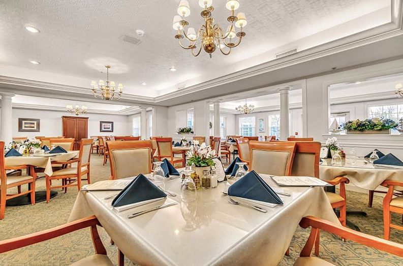An elegant dining room with neatly arranged tables and chandeliers.