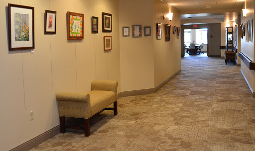 A well-lit hallway featuring framed artwork on the walls and a cozy bench.