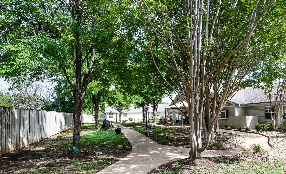 A scenic garden pathway lined with lush trees and greenery.