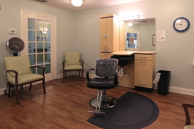 A well-lit hair salon with a styling chair, mirrors, and comfortable seating.