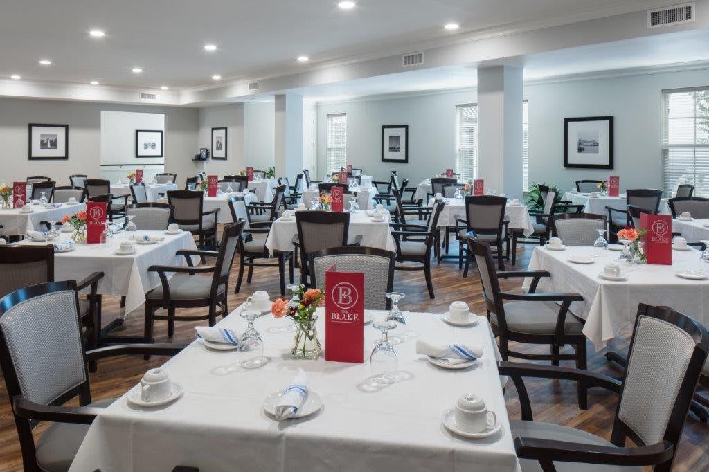 An elegant dining room setup with neatly arranged tables and chairs, featuring white tablecloths.