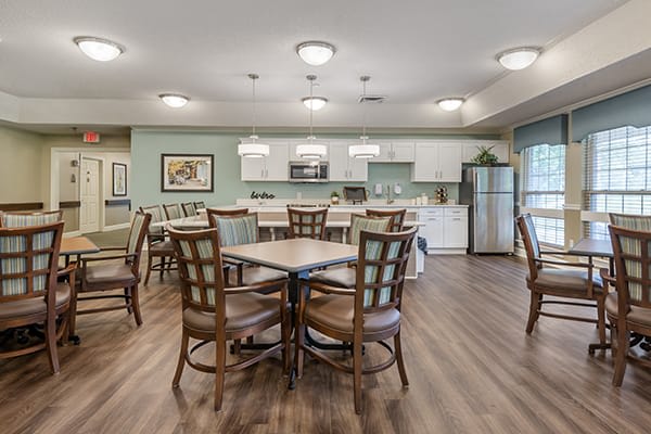 A modern kitchen and dining area with wooden tables and chairs, featuring contemporary lighting fixtures and a bright atmosphere.