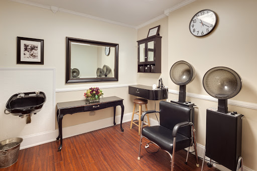 A cozy hair salon interior featuring a mirror, styling station, and comfortable seating.