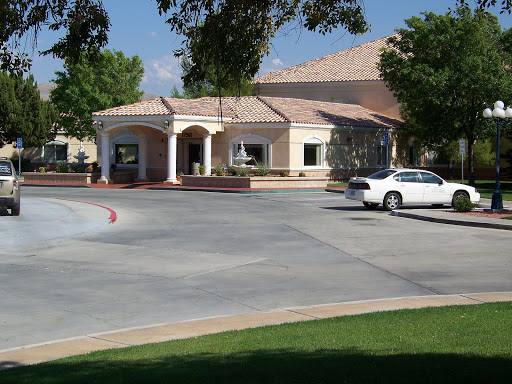 A well-designed building surrounded by greenery and a spacious parking area.