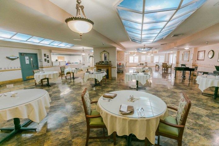 An elegant dining room setup with neatly arranged tables and chairs under a chandelier.