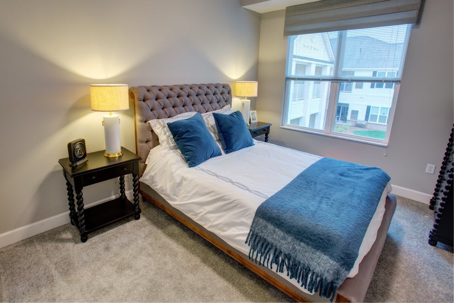 A modern bedroom featuring a neatly made bed with blue accents and soft lighting from bedside lamps.