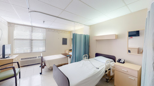 A view of a hospital patient room featuring two beds and a privacy curtain.