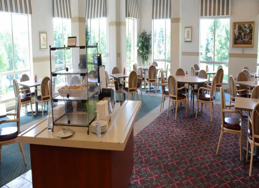 An empty dining area with tables and chairs, featuring a food display counter.