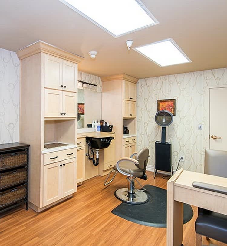 A clean and organized hair salon interior featuring styling chairs, equipment, and cabinets.
