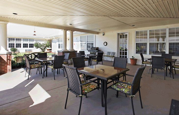 A covered outdoor patio area with tables and chairs arranged for seating.