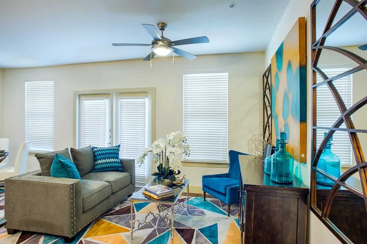 A modern living room with colorful decor, including a patterned rug and abstract art.