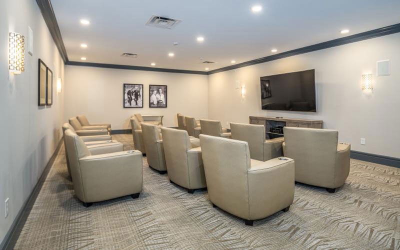 A modern theater room with comfortable seating and a large television screen.