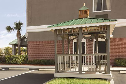 A charming gazebo with a green roof, providing a cozy outdoor space near a building.