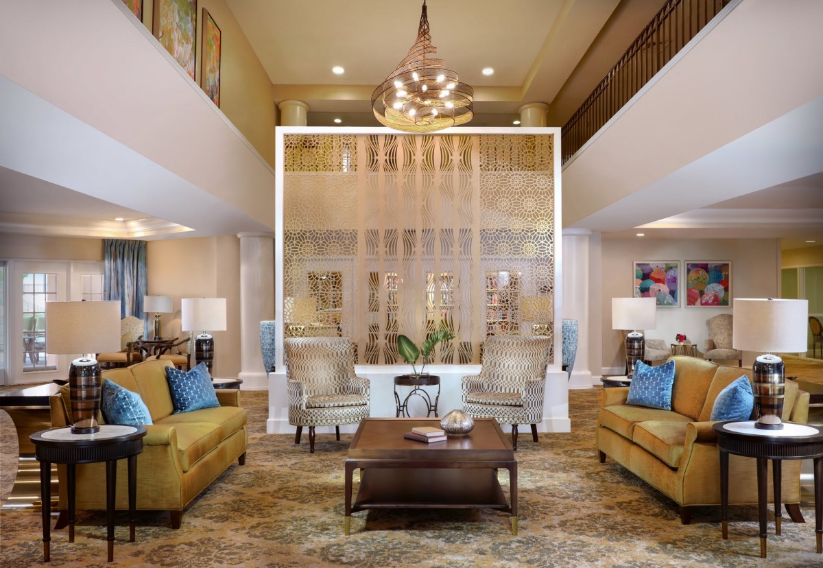 A modern living room with sophisticated decor, featuring comfortable sofas and chairs, a central coffee table, and an elegant chandelier.