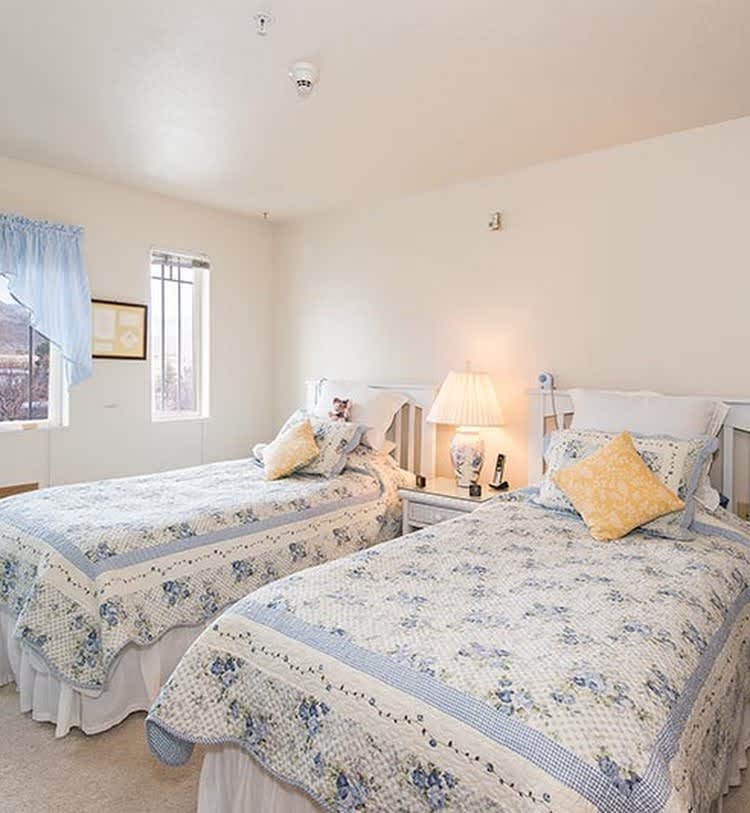 A cozy bedroom with twin beds adorned in floral-patterned bedding, featuring a soft, neutral color palette.