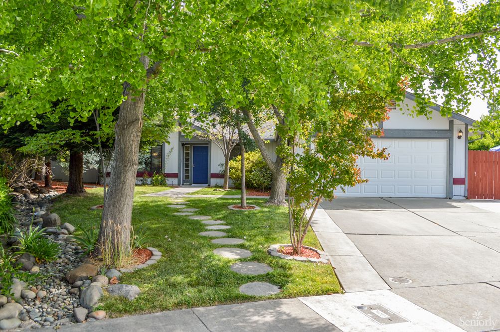 A charming residential house with a well-maintained front yard featuring lush greenery and a stone pathway.