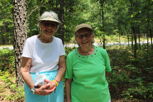Two smiling elderly women enjoying a sunny day in nature.