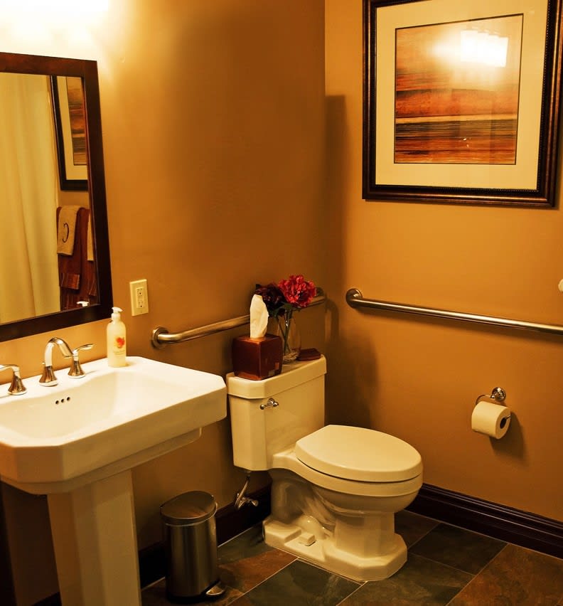 A well-decorated bathroom featuring a pedestal sink, toilet, and wall artwork.