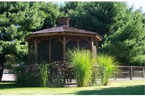 A wooden gazebo surrounded by lush green foliage in a garden setting.