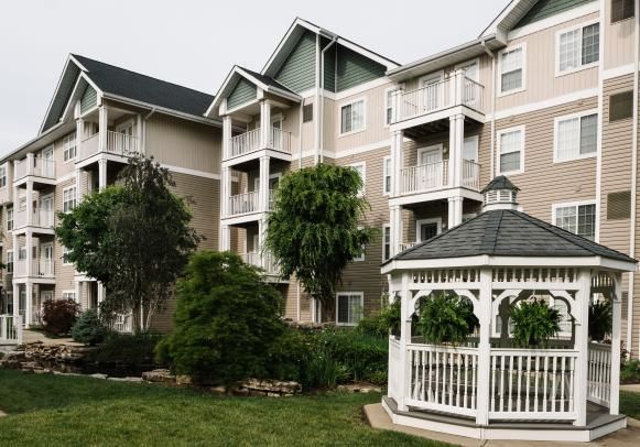 A residential apartment complex with a white gazebo set amidst lush greenery.