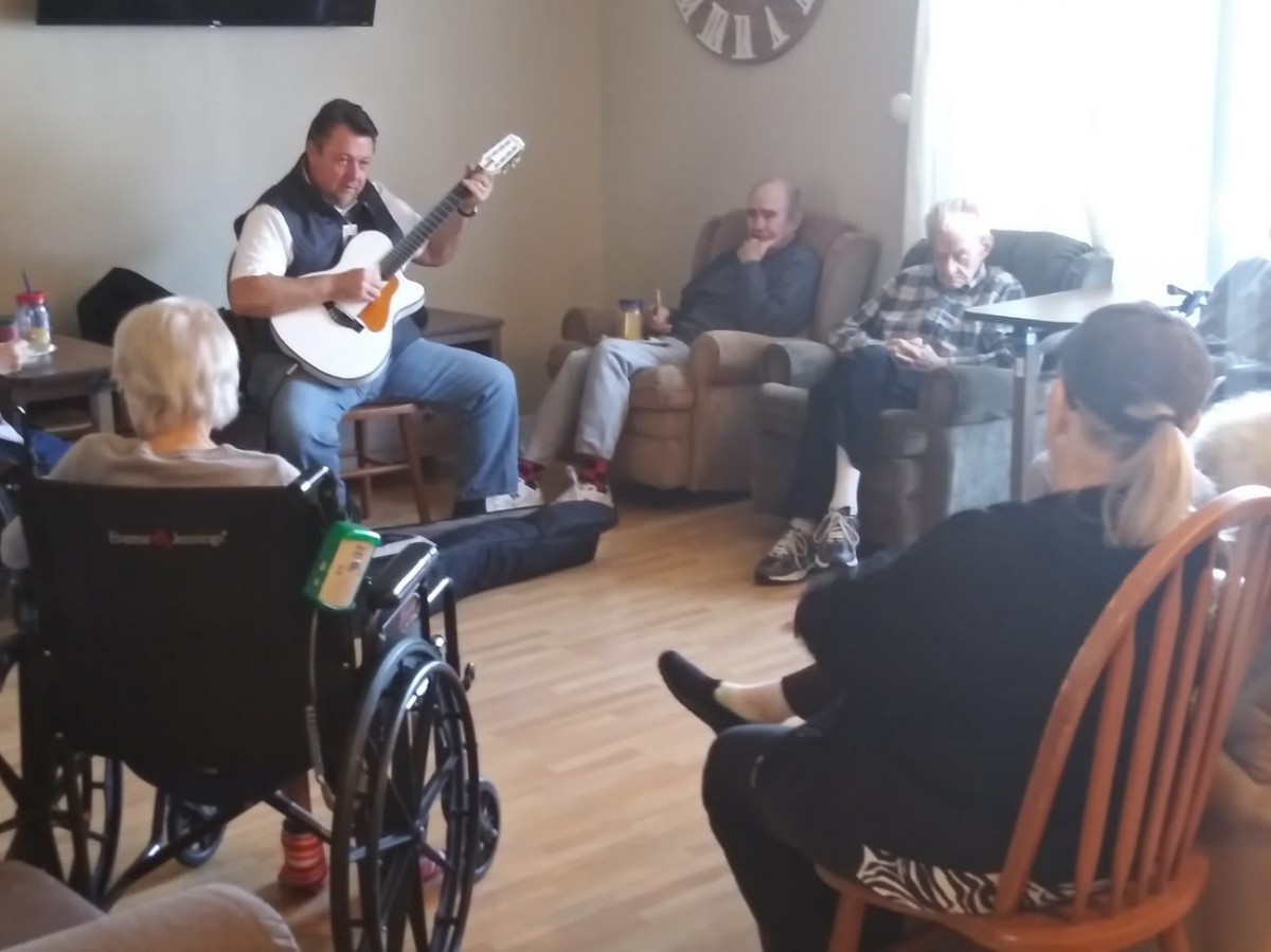 A musician playing guitar for an audience in a nursing home.