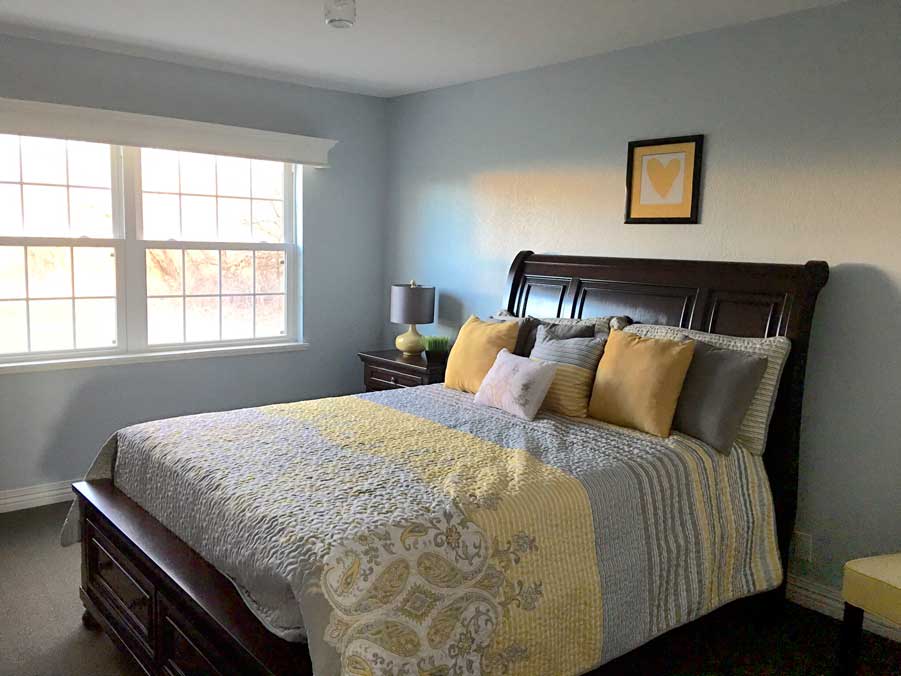 A cozy bedroom with a neatly made bed, featuring patterned bedding and decorative pillows.