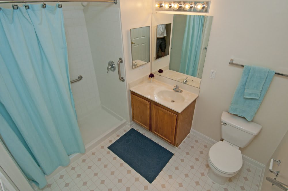 A clean and well-organized bathroom with a shower, sink, vanity, and blue accents.
