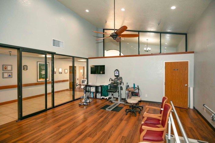 A spacious medical office with wooden flooring, seating area, and medical equipment.