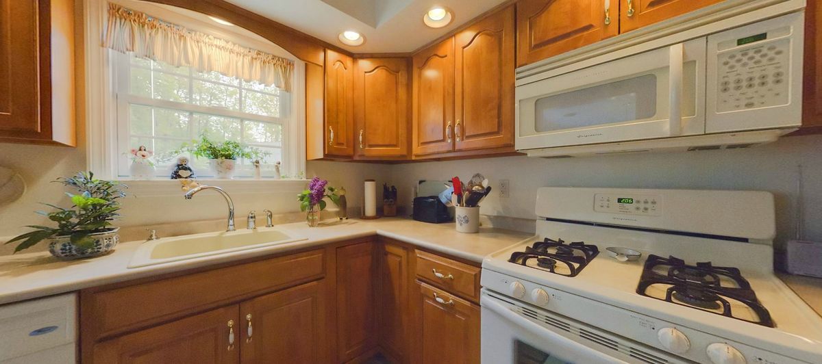 A cozy kitchen with wooden cabinets, a gas stove, and a microwave.
