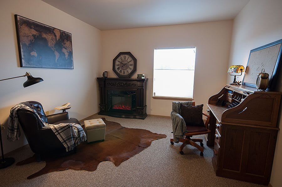 Cozy living room with a fireplace, desk, and armchair.